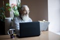 Senior man reading book and using laptop at library Royalty Free Stock Photo