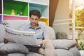 Senior man reading Business News newspaper on sofa in living room at home Royalty Free Stock Photo