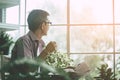 Senior man reading newspaper and drinking coffee in peaceful greenhouse garden Royalty Free Stock Photo