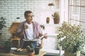 Senior man reading newspaper and drinking coffee in peaceful greenhouse garden Royalty Free Stock Photo