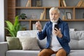 Senior man receives shocking news through smartphone at home Royalty Free Stock Photo