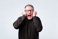 Senior man in red shirt plugging ears with fingers Royalty Free Stock Photo