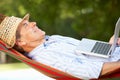 Senior Man Relaxing In Hammock With Laptop Royalty Free Stock Photo