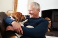 Senior Man Relaxing At Home With Pet Dog