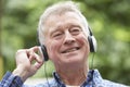 Senior Man Relaxing Listening To Music On Headphones In Garden Royalty Free Stock Photo