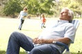 Senior Man Relaxing In Park With Grandchildren