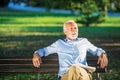 Senior man relaxing in park on a sunny day seated on a wooden bench and waiting for someone Royalty Free Stock Photo