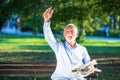 Senior man relaxing in park on a sunny day seated on a wooden bench and waiting for someone Royalty Free Stock Photo