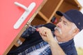 Senior man repairing gate lock with screwdriver