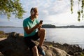 Senior man rest on stone by river after run training in morning Royalty Free Stock Photo