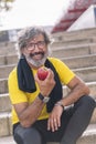 senior man rests eating an apple after workout Royalty Free Stock Photo