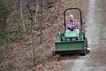 Senior man rides John Deere on edge of rocky path