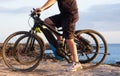 Senior man riding his bici on the cliffs. Horizon over sea at sunset light. Two electric bicycles with battery and engine. One Royalty Free Stock Photo