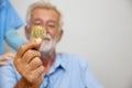 Senior man`s hand holding bitcoin coin. Senior businessman hold a gold bitcoin coin in hand. Cryptocurrency business concept. Elec