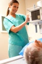 Senior man in 60s undergoing x-ray scan with smiling female doctor at the scanner machine Royalty Free Stock Photo