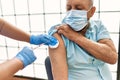Senior man with safety mas getting vaccinated with covid 19 immunity vaccine, nurse injecting prevention vaccine