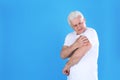 Senior man scratching arm on color background. Allergy symptom Royalty Free Stock Photo