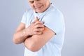 Senior man scratching arm on grey background. Allergy symptom Royalty Free Stock Photo