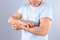 Senior man scratching forearm on grey background. Allergy symptom Royalty Free Stock Photo