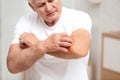 Senior man scratching forearm indoors. Allergy symptom Royalty Free Stock Photo