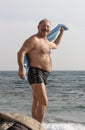 Senior man after sea bathing. Hardening procedure. Winter clothes on foreground Royalty Free Stock Photo