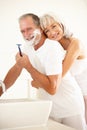 Senior Man Shaving In Bathroom Mirror With Wife Royalty Free Stock Photo