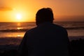Senior man silhouette relaxing looking at the horizon the magnificent orange sunset at sea