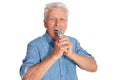 Senior man singing into microphone on white background Royalty Free Stock Photo