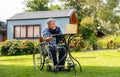 Senior man sit on wheelchair enjoy and relax with laptop outdoor in the garden with warm light Royalty Free Stock Photo