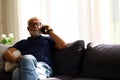 Senior man sitting alone in home and talking friend on smart phone. Royalty Free Stock Photo