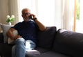 Senior man sitting alone for relaxation and playing game on smart phone in home Royalty Free Stock Photo