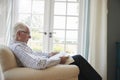 Senior man sitting in an armchair reading a book, close up Royalty Free Stock Photo
