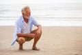 Senior man sitting on beach relaxing . Happy retired man relaxed on sand outdoors Royalty Free Stock Photo