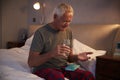 Senior Man Sitting On Bed At Home Taking Medication Royalty Free Stock Photo