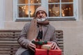 Senior man sitting on a bench, holding a lot of Chrismtas gifts in his hands. Christmas shopping spree. Royalty Free Stock Photo