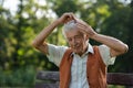 Senior man sitting on a bench in the park and combing his hair. Royalty Free Stock Photo