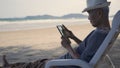 Senior man sitting on chairs enjoying time on beach travel vacation using tablet computer Royalty Free Stock Photo