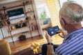 Senior man on a sofa holding remote home control system on a digital tablet Royalty Free Stock Photo