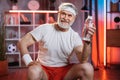 Senior man sitting on fitball with bottle of water in hand