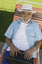 Senior Man sitting on Lawn Chair Using Laptop elevated view portrait.