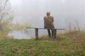 Senior man sitting lonely on a bench on riverside