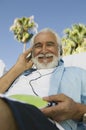Senior Man sitting outdoors listening to headphones low angle portrait. Royalty Free Stock Photo