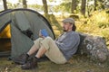 Senior man sitting outside a tent reading a book