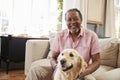 Senior Man Sitting On Sofa At Home With Pet Labrador Dog Royalty Free Stock Photo