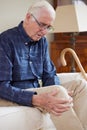 Senior Man Sitting On Sofa At Home Suffering With Knee Pain From Arthritis Royalty Free Stock Photo