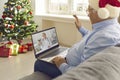 Senior man sitting on sofa at home and waving hand at laptop screen greeting online doctor Royalty Free Stock Photo