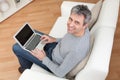 Senior man sitting in sofa and using laptop Royalty Free Stock Photo