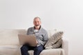 Senior man sitting on sofa, working on laptop. Royalty Free Stock Photo