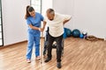 Senior man sitting on wheelchair being assited by geriatric nurse, handicapped mature man getting help to stand up Royalty Free Stock Photo