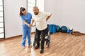 Senior man sitting on wheelchair being assited by geriatric nurse, handicapped mature man getting help to stand up Royalty Free Stock Photo